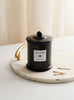 Unlit Vanilla Oud candle beside matches in soft sunlight