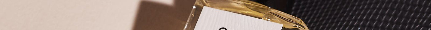 Royal Oud perfume oil resting on a black handbag with a gold chain