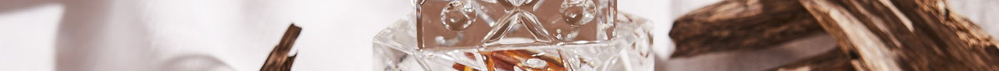 Crystal bottle of pure oud oil among agarwood chips on white linen