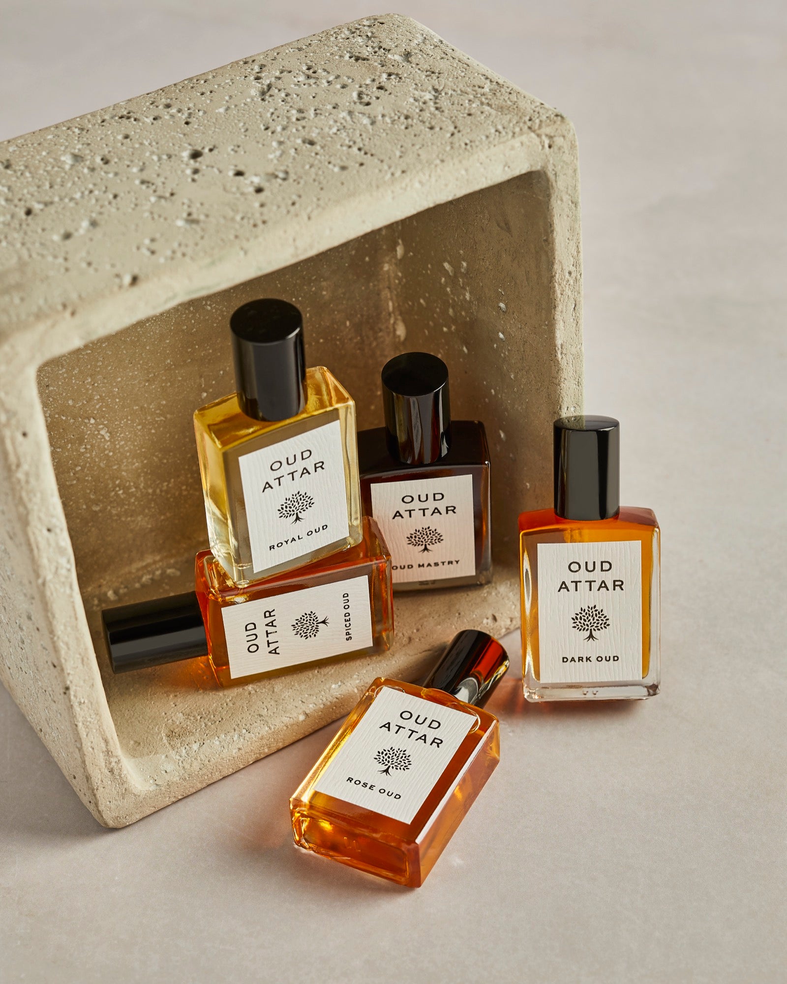 Five Oud Attar attar bottles resting in a stone box